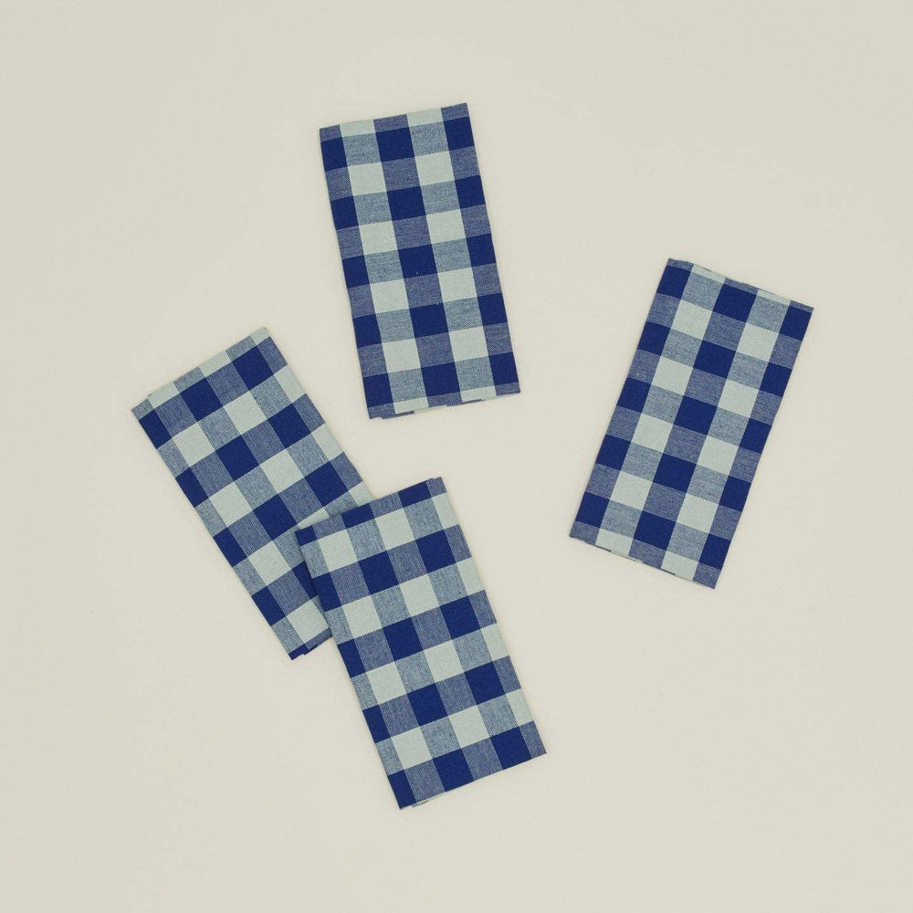 Four blue and white checkered napkins on a beige background