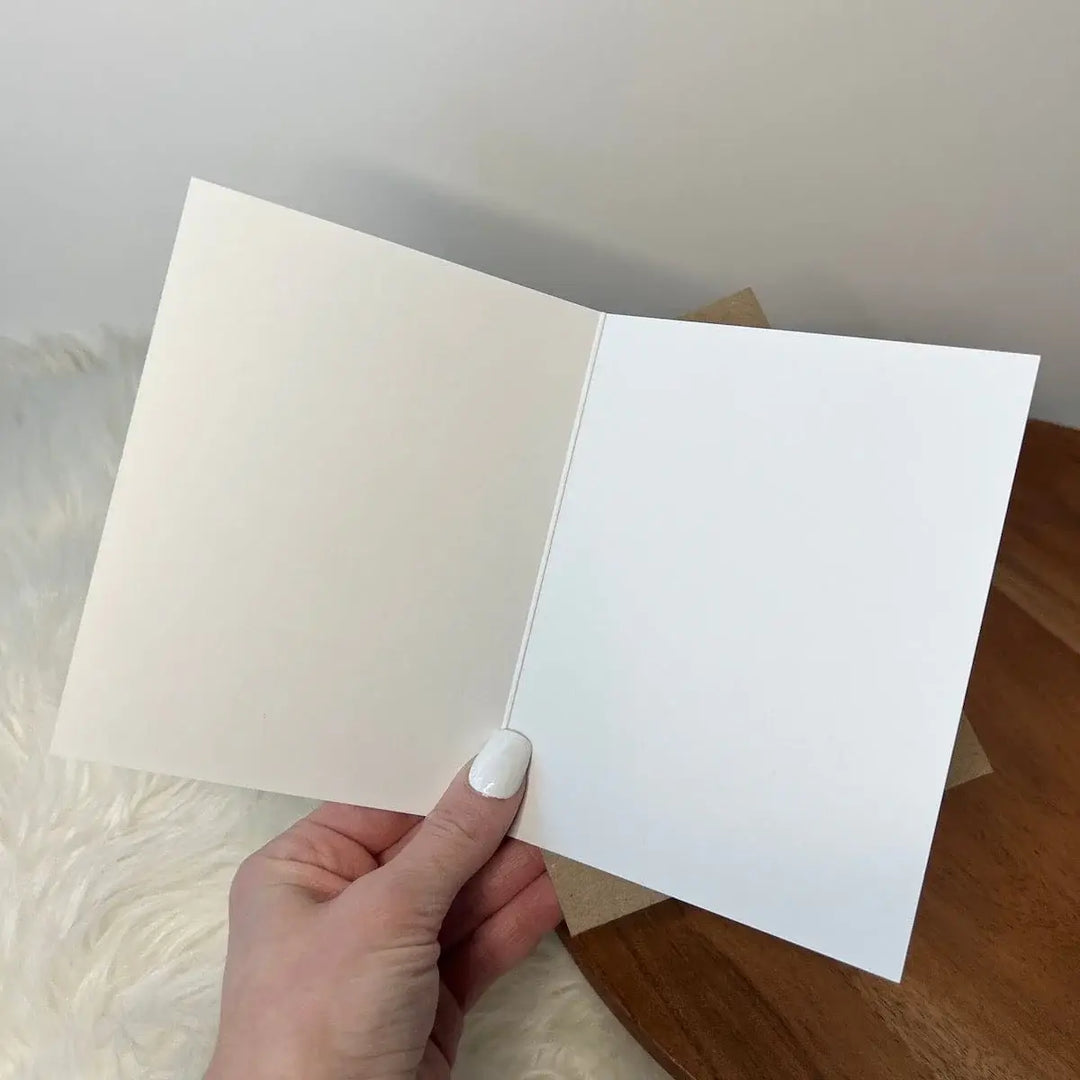 Hand holding a white card against a neutral background