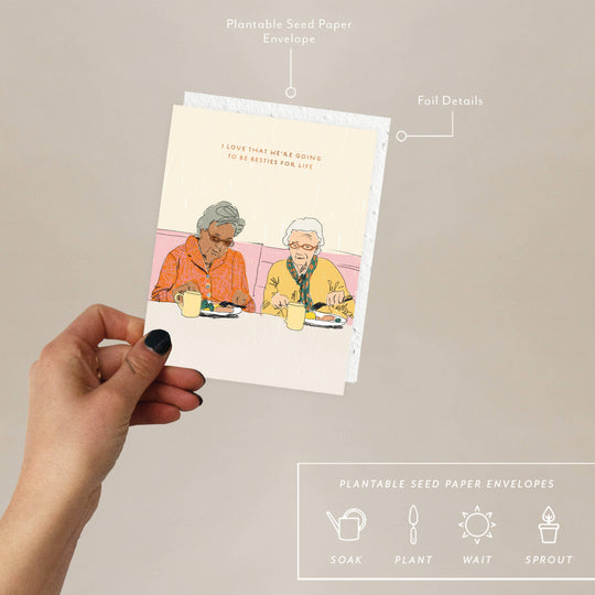 Hand holding a card with illustration of two people eating, labeled 'Plantable Seed Paper Envelopes'.