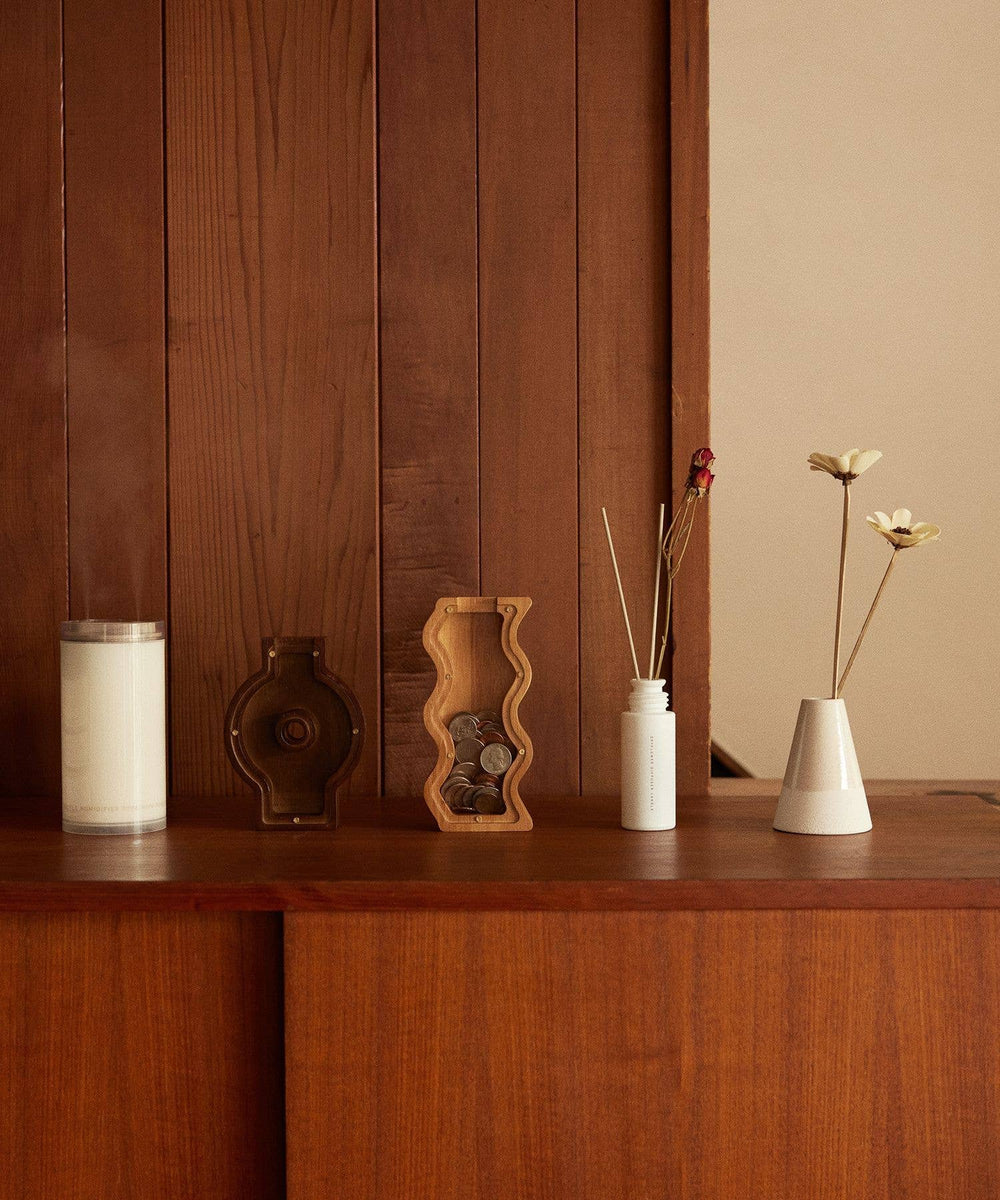 Decorative items on a wooden shelf against a wooden wall.