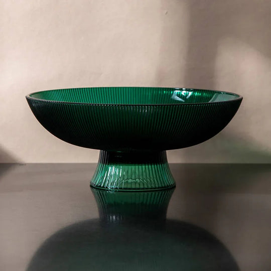 Green ceramic bowl on a reflective surface with a neutral background
