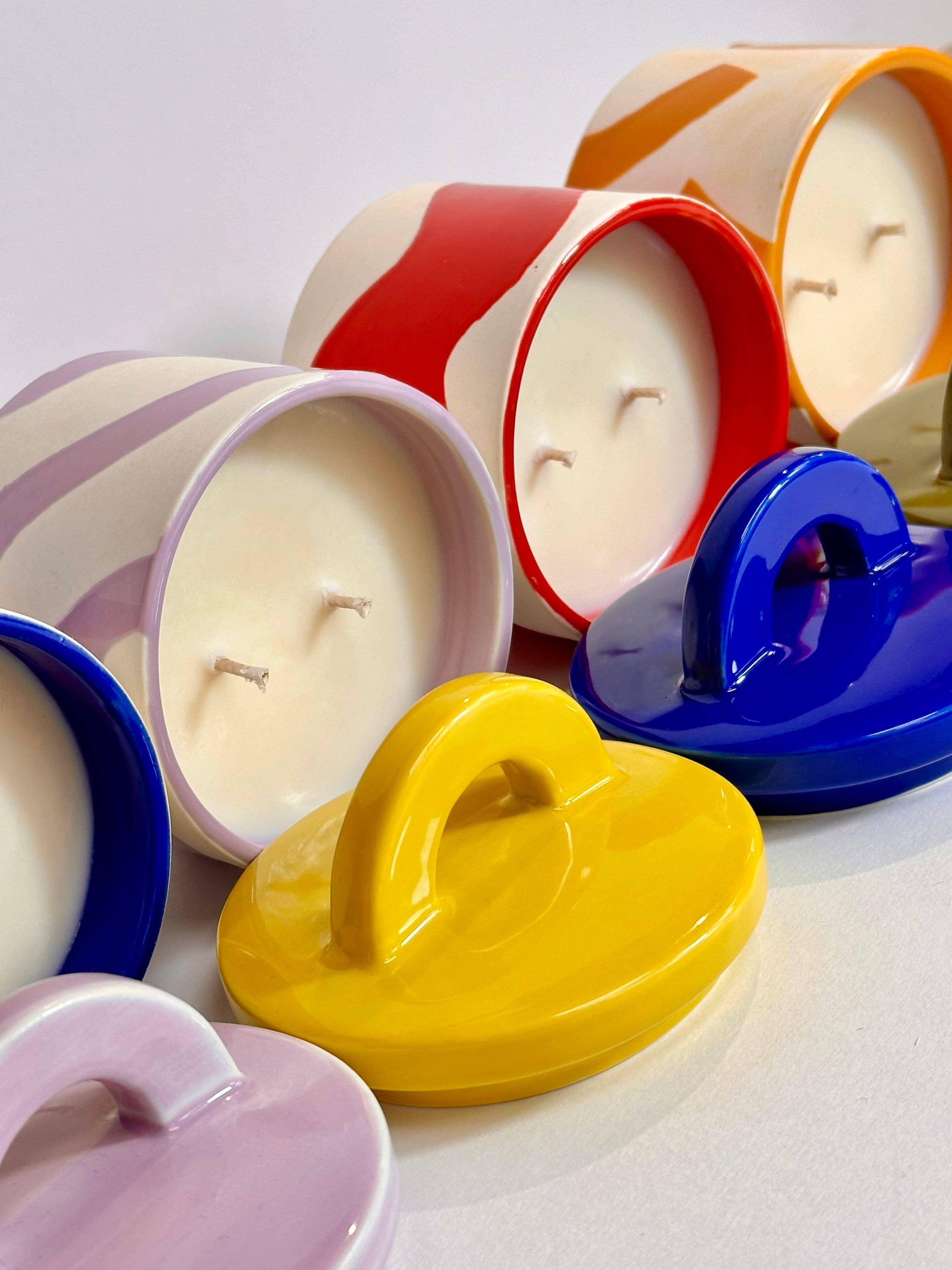 Colorful ceramic candles with vibrant lids, perfect for home decor and gifting.