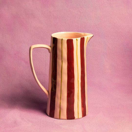 Ceramic pitcher with striped design on a pink background