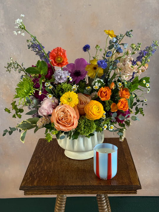 Colorful flower arrangement on a table with a candle.