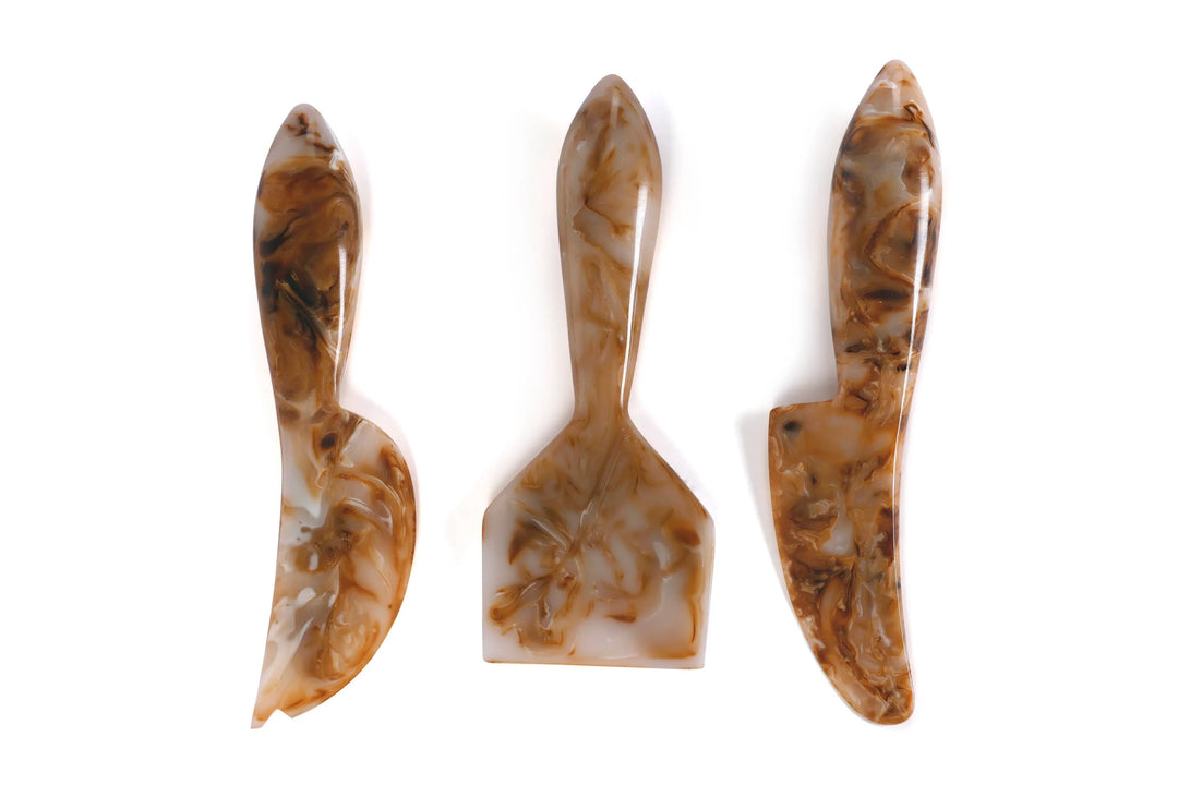 Three marbled brown and beige ceramic tools on a white background