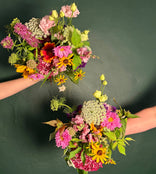 Two hand held bouquet of mixed wildflowers.