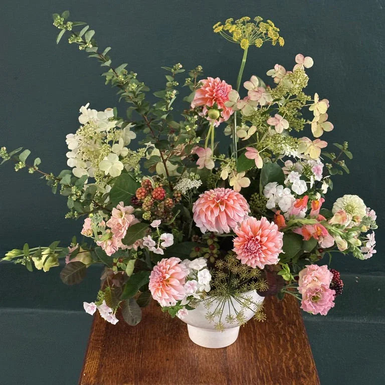 Fresh seasonal flower arrangement with pink dahlias, hydrangeas, and greenery in a white vase