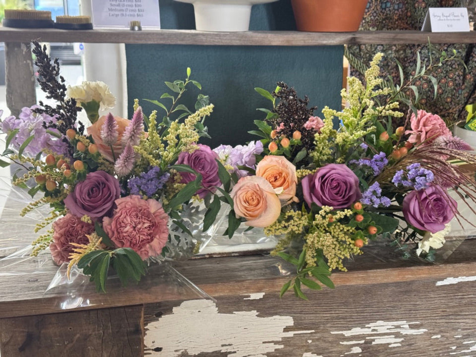 Two fall bouquets with peach and lavender roses and goldenrod on a rustic table at Blooms Collective in Dupont Circle