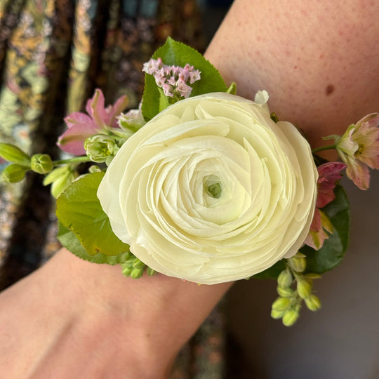 White flower corsage on a wrist with a blurred background