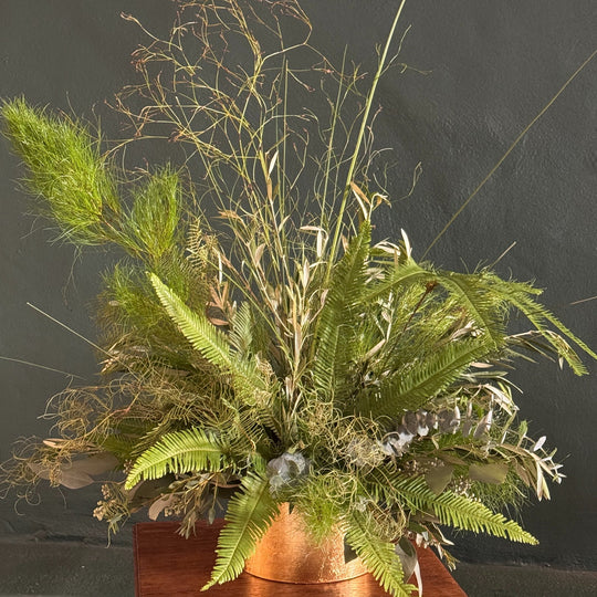 Decorative arrangement of greenery on a wooden base against a dark background