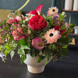 Bouquet of flowers in a white vase on a dark surface with a blurred background