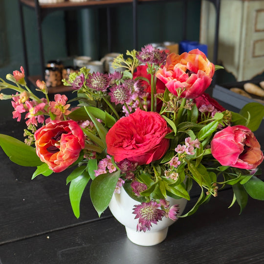 Bouquet of flowers in a white vase on a dark surface with a blurred background