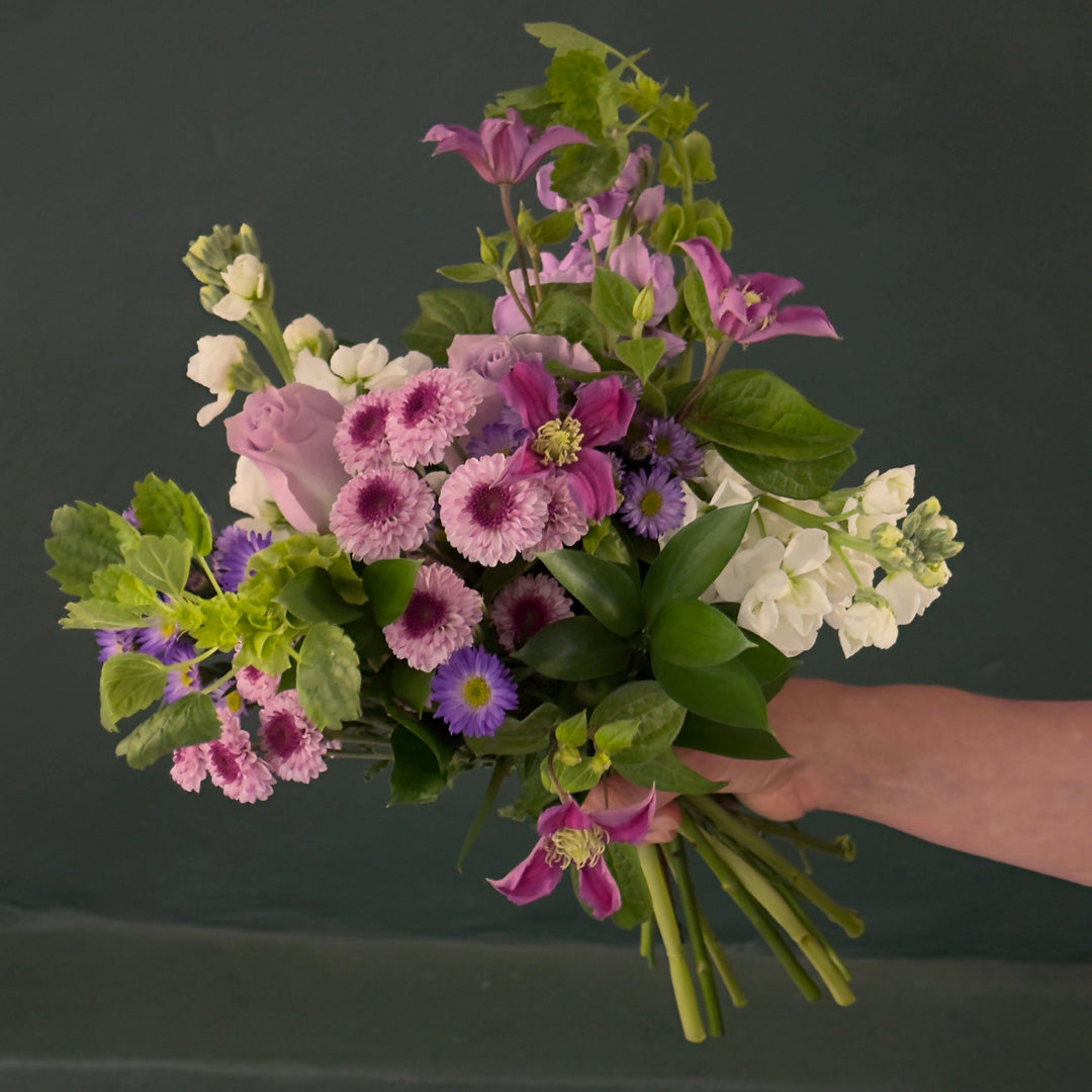 Bouquet of flowers held by a hand against a dark background