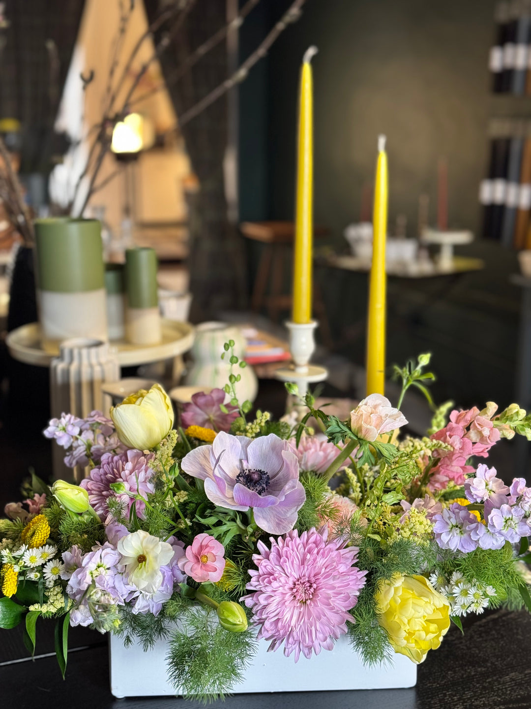Floral arrangement with colorful flowers and candles on a table.