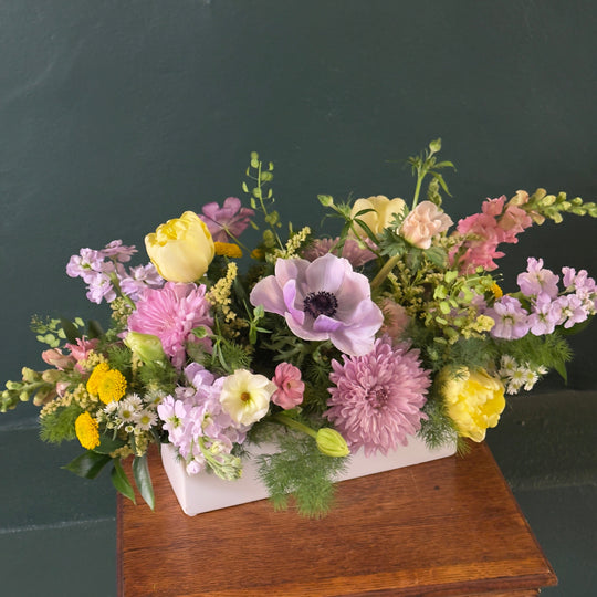 Floral arrangement on a wooden table with a dark background