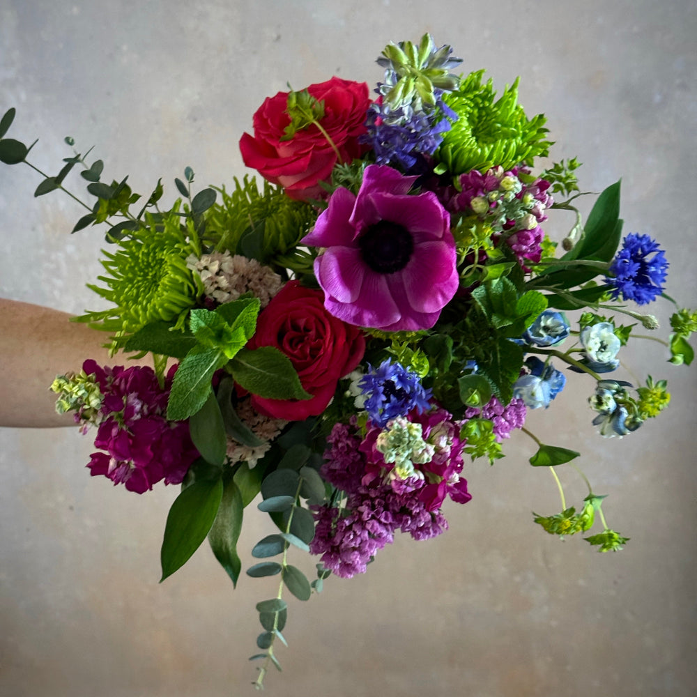 Bouquet of colorful flowers held against a neutral background