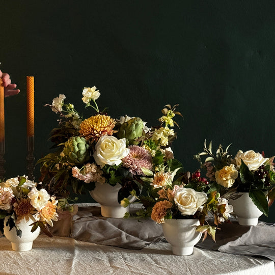 Person arranging flowers on a table with a dark background
