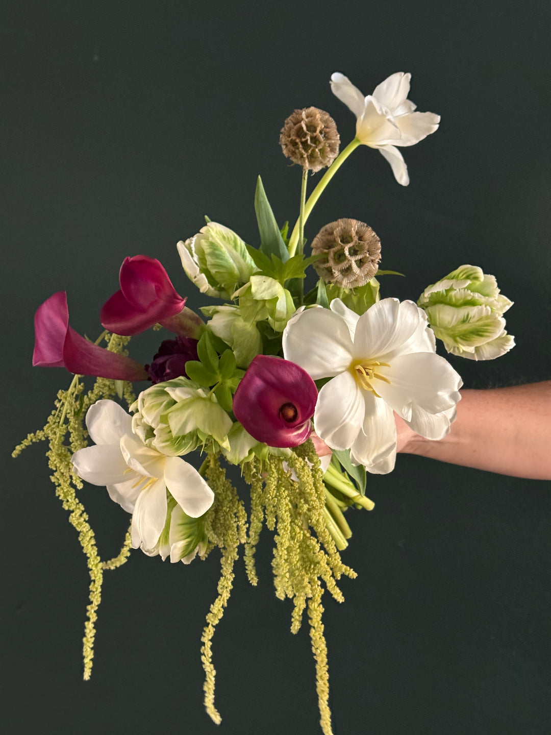 Bouquet of flowers held by a hand against a black background
