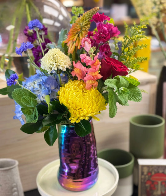 Colorful bouquet of flowers in a iridescent vase on a table.
