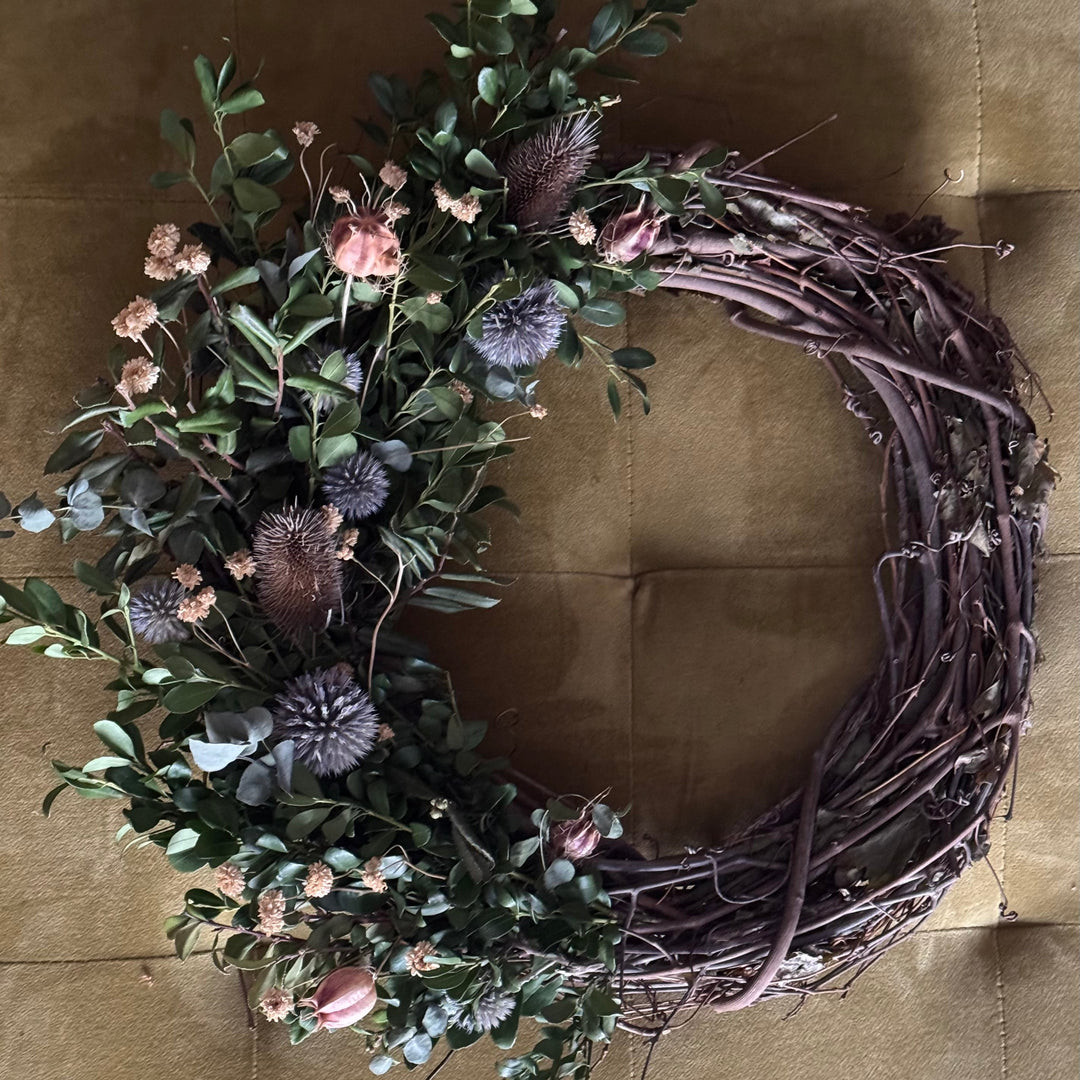 Decorative wreath with greenery and flowers on a brown background