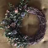 Decorative wreath with greenery and flowers on a brown background