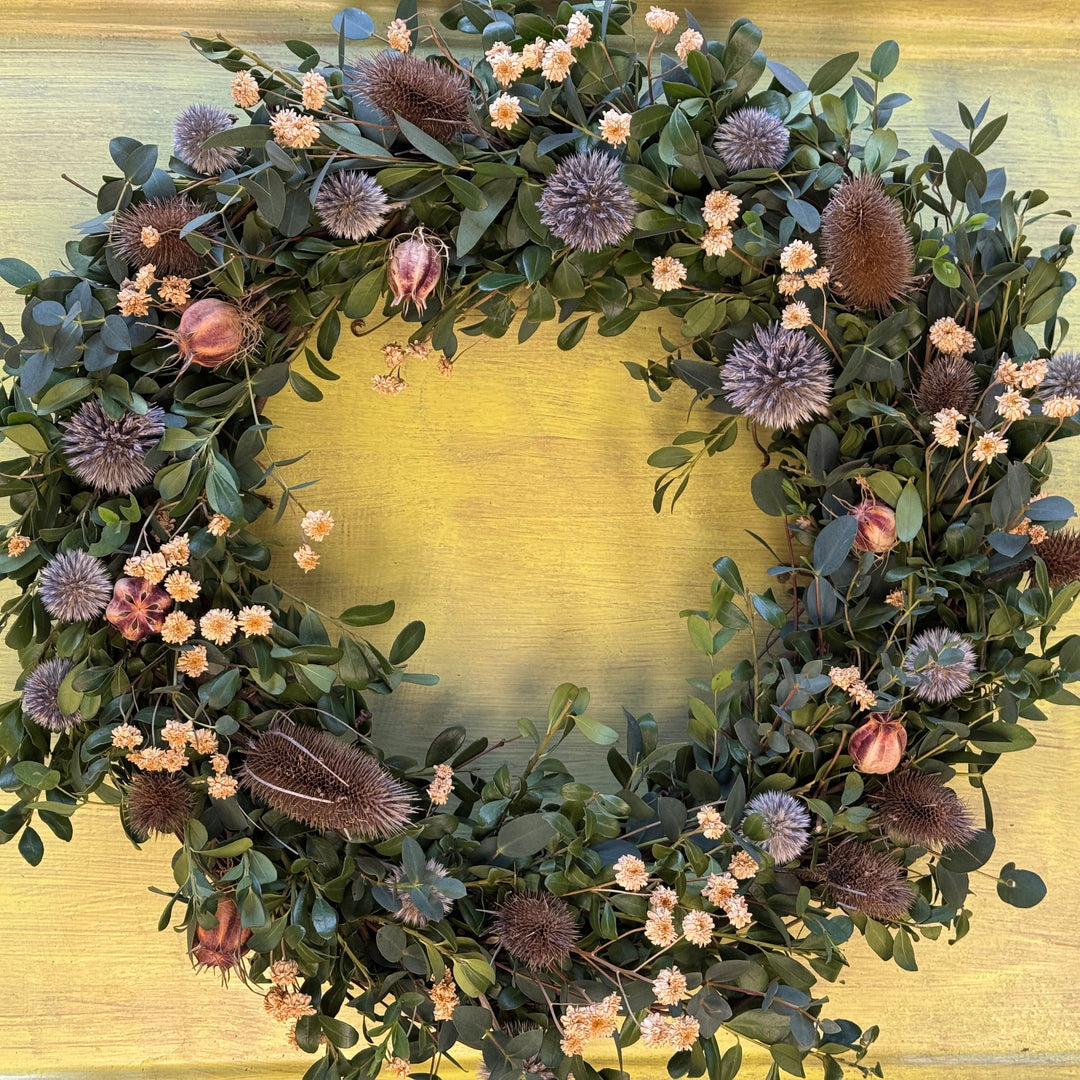 Floral wreath with greenery and flowers on a gold background