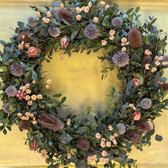 Floral wreath with greenery and flowers on a gold background