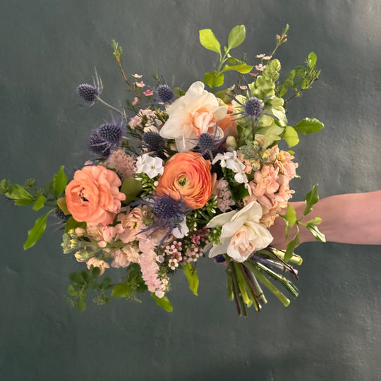 Bouquet of flowers held by a person against a dark background