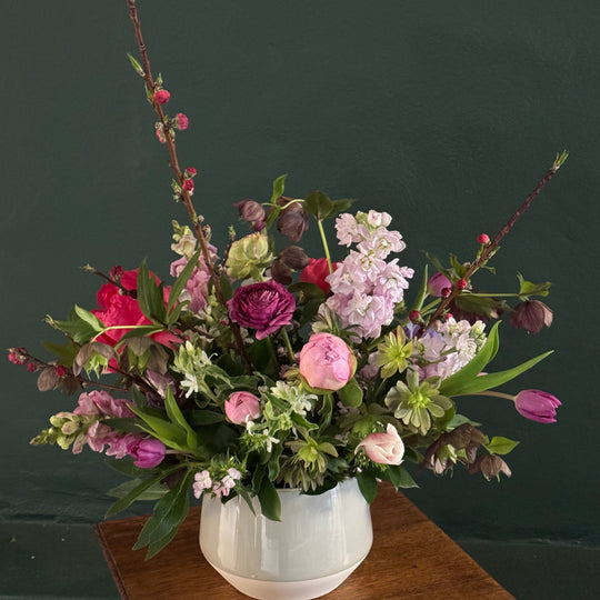 Floral arrangement on a wooden stand against a dark background