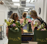 People in a workshop setting with floral arrangements.