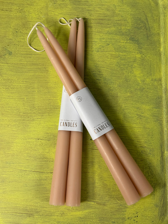 Two pairs of beige candle holders on a green wooden surface.