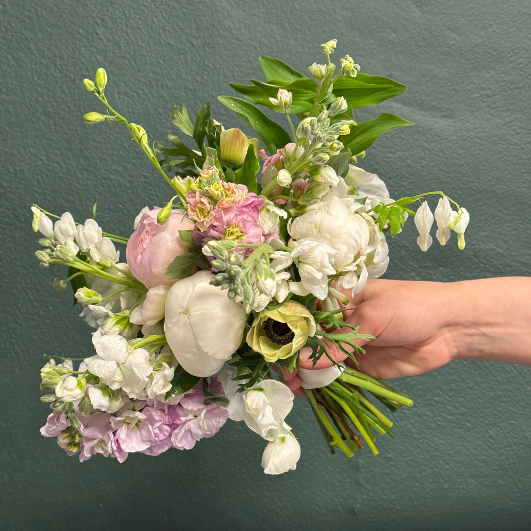 Hand holding a bouquet of flowers against a dark background