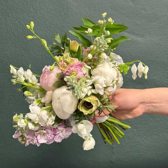 Hand holding a bouquet of flowers against a dark background