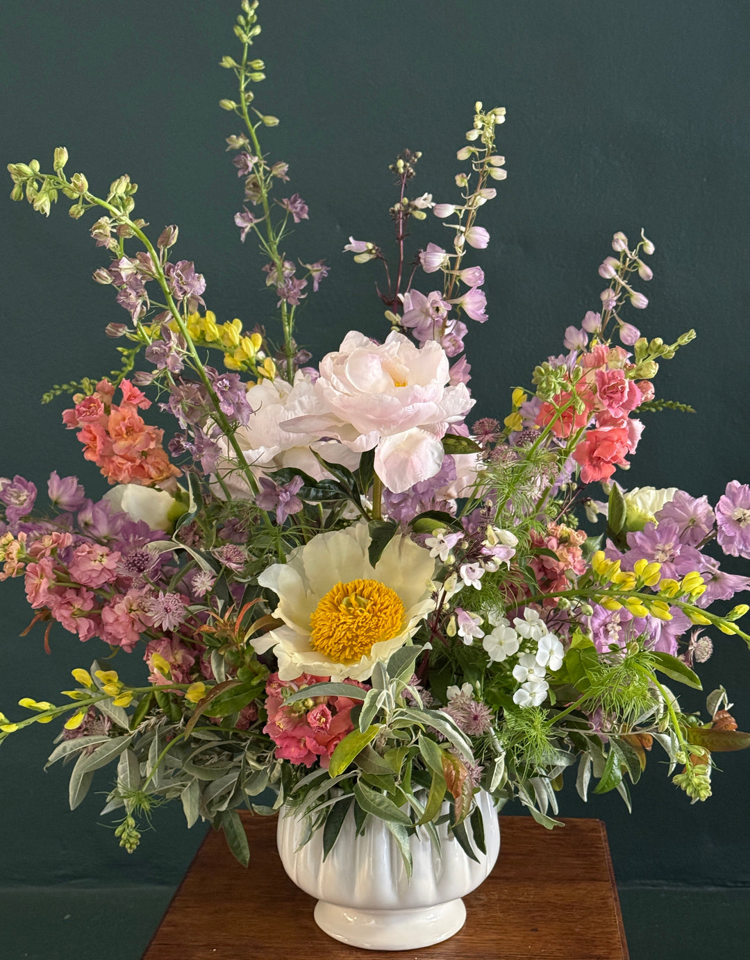 Bouquet of colorful flowers in a white vase against a dark background
