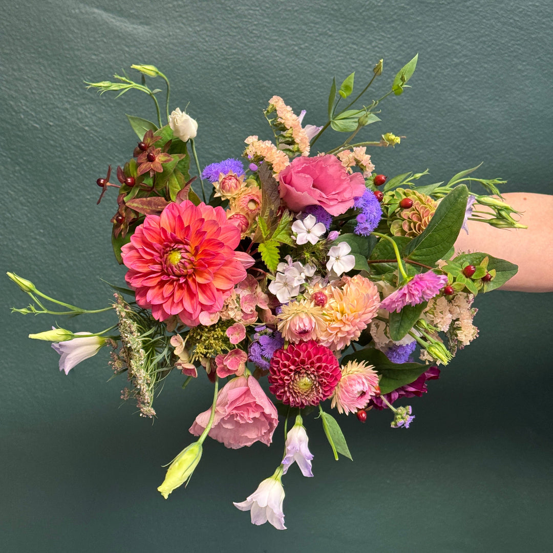 Bouquet of colorful flowers held against a dark green background