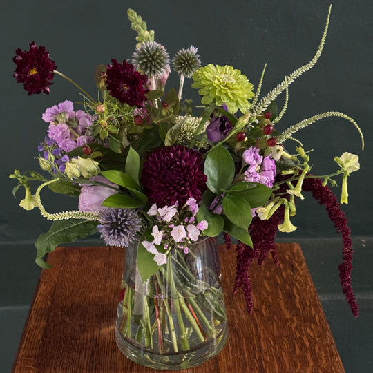 Bouquet of flowers in a clear vase on a wooden surface with a dark background