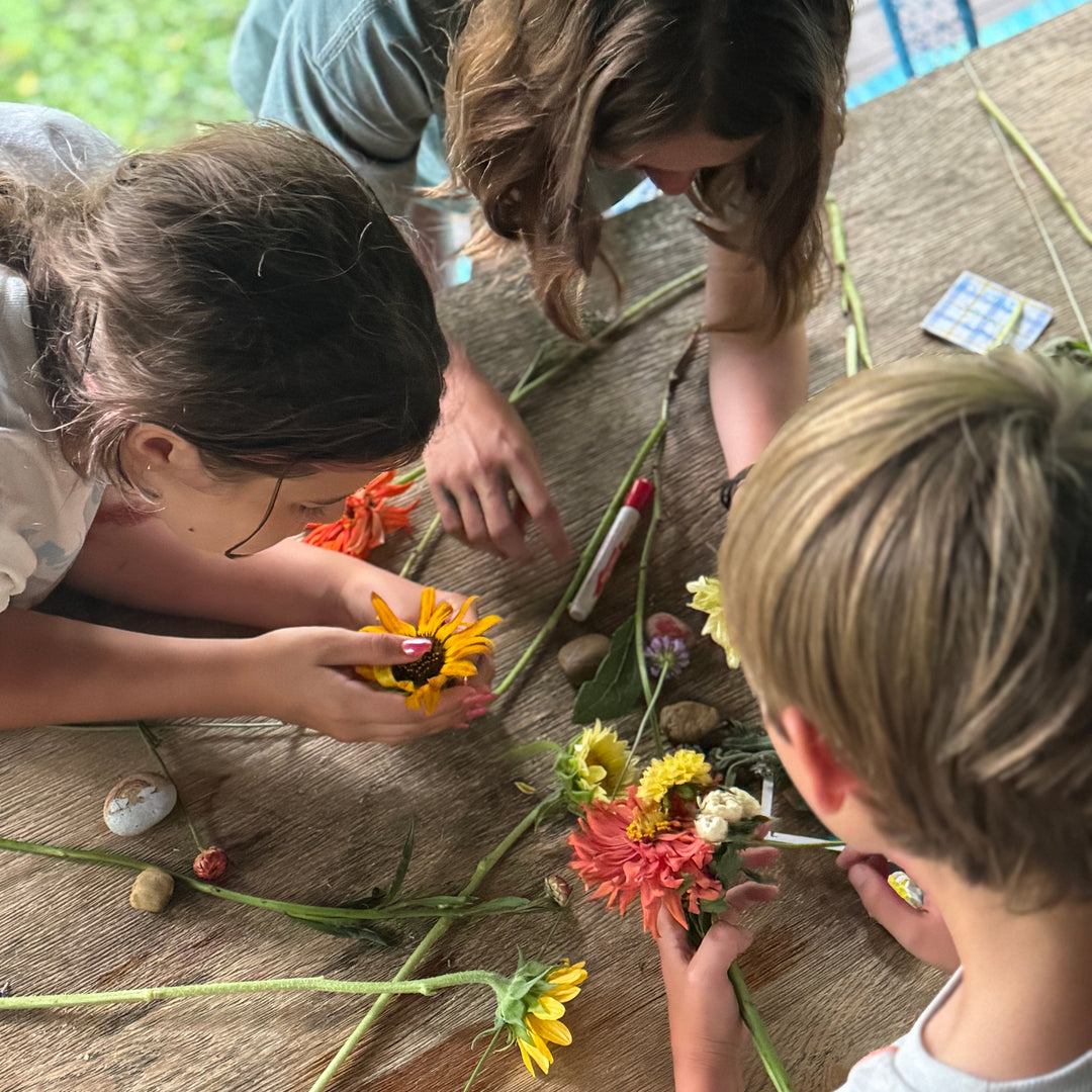 Three children arranging flowers on a wooden surface