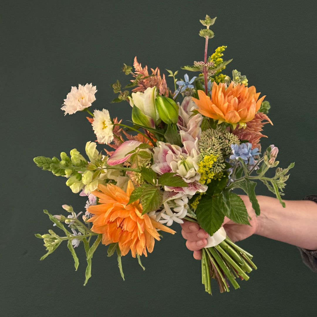 Bouquet of flowers held by a hand against a dark background