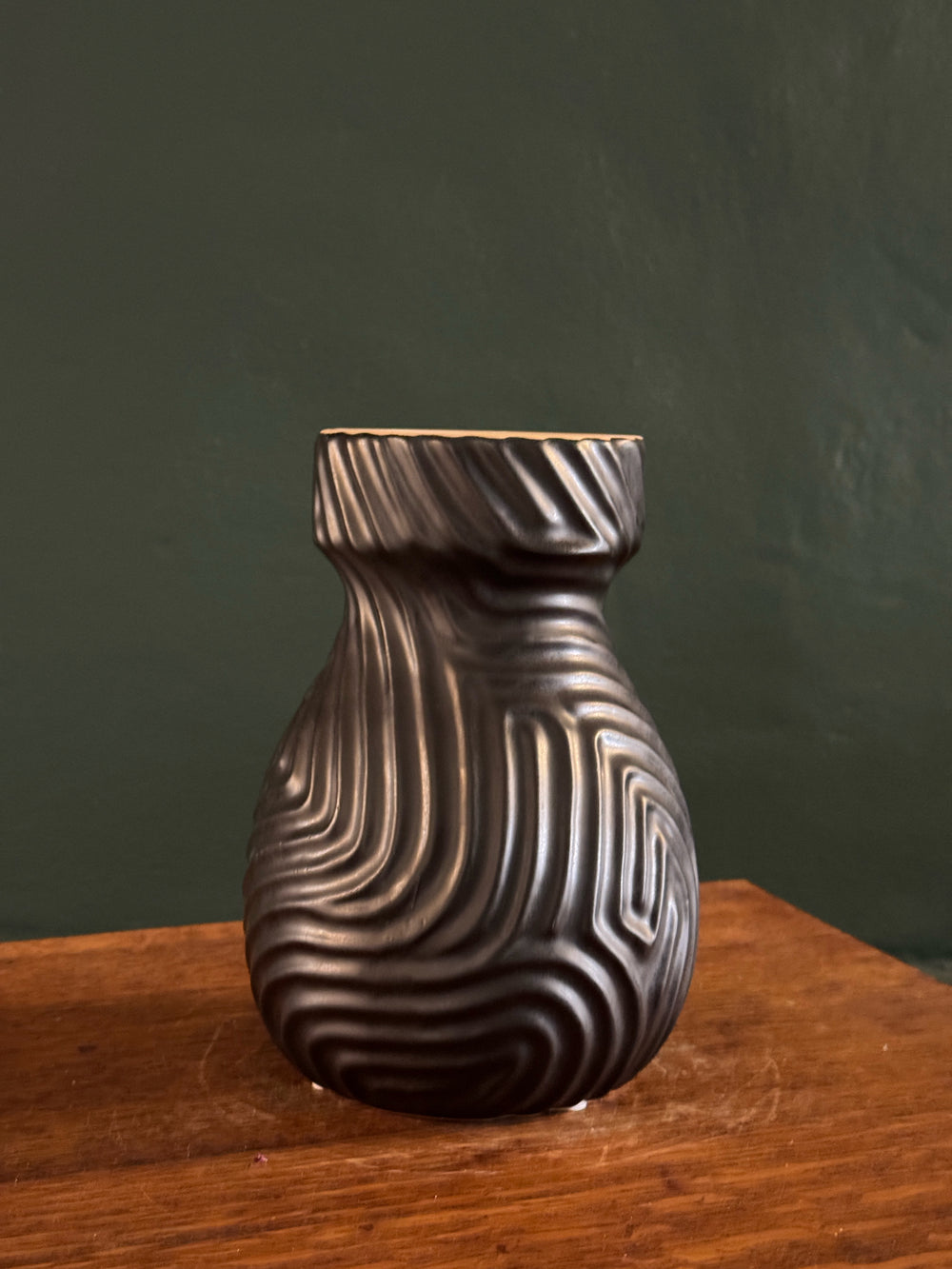 Decorative metal knob on a wooden surface with a dark green background