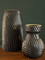 Decorative metal vase with wavy pattern on a wooden surface