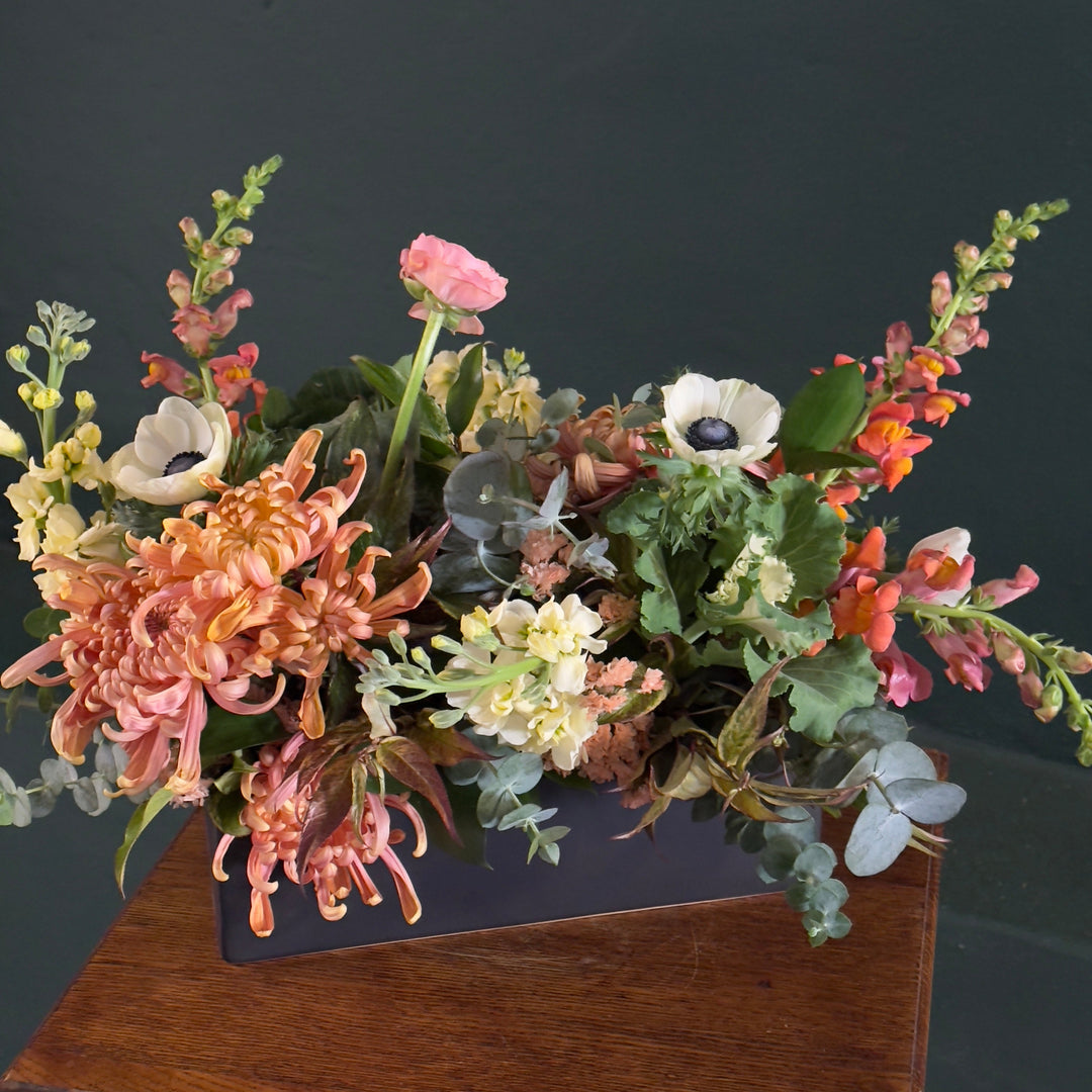 Floral arrangement on a wooden surface with a dark background
