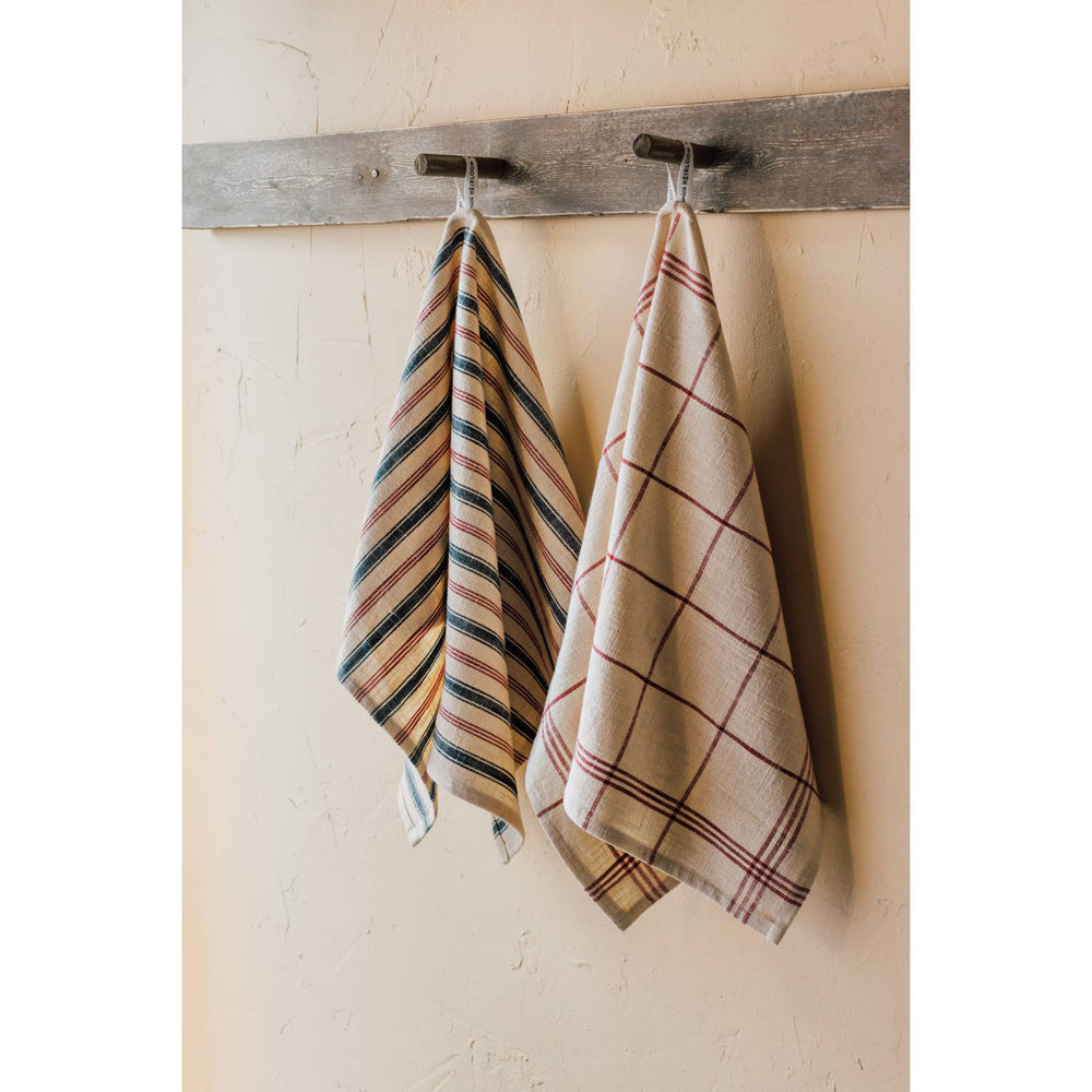 Two plaid towels hanging on a wooden rack against a beige wall.