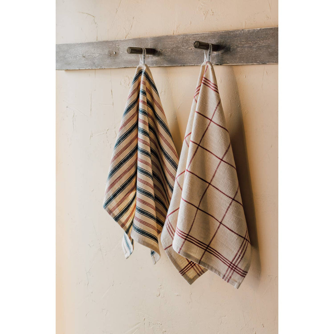 Two plaid towels hanging on a wooden rack against a beige wall.
