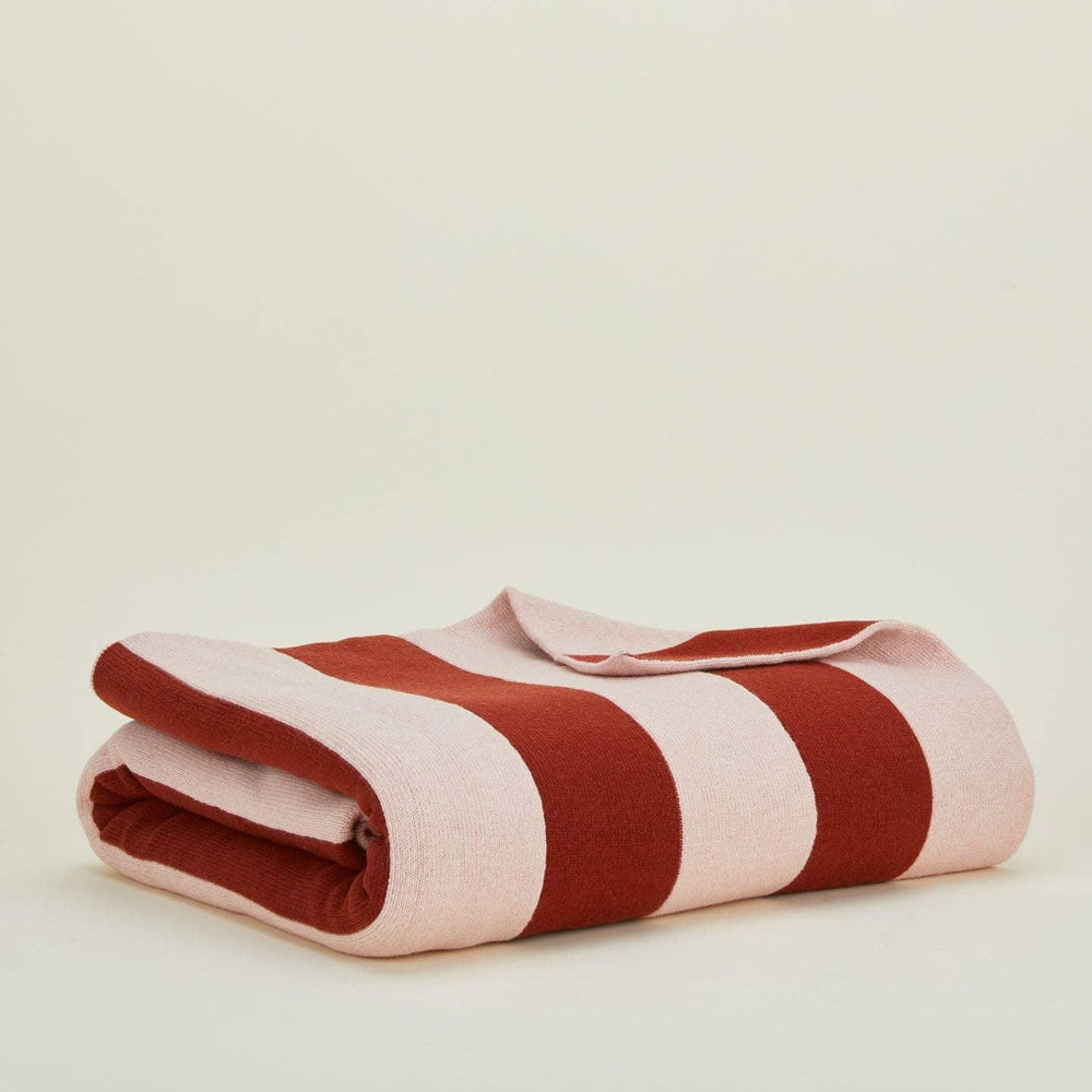 Folded red and white striped blanket on a beige background