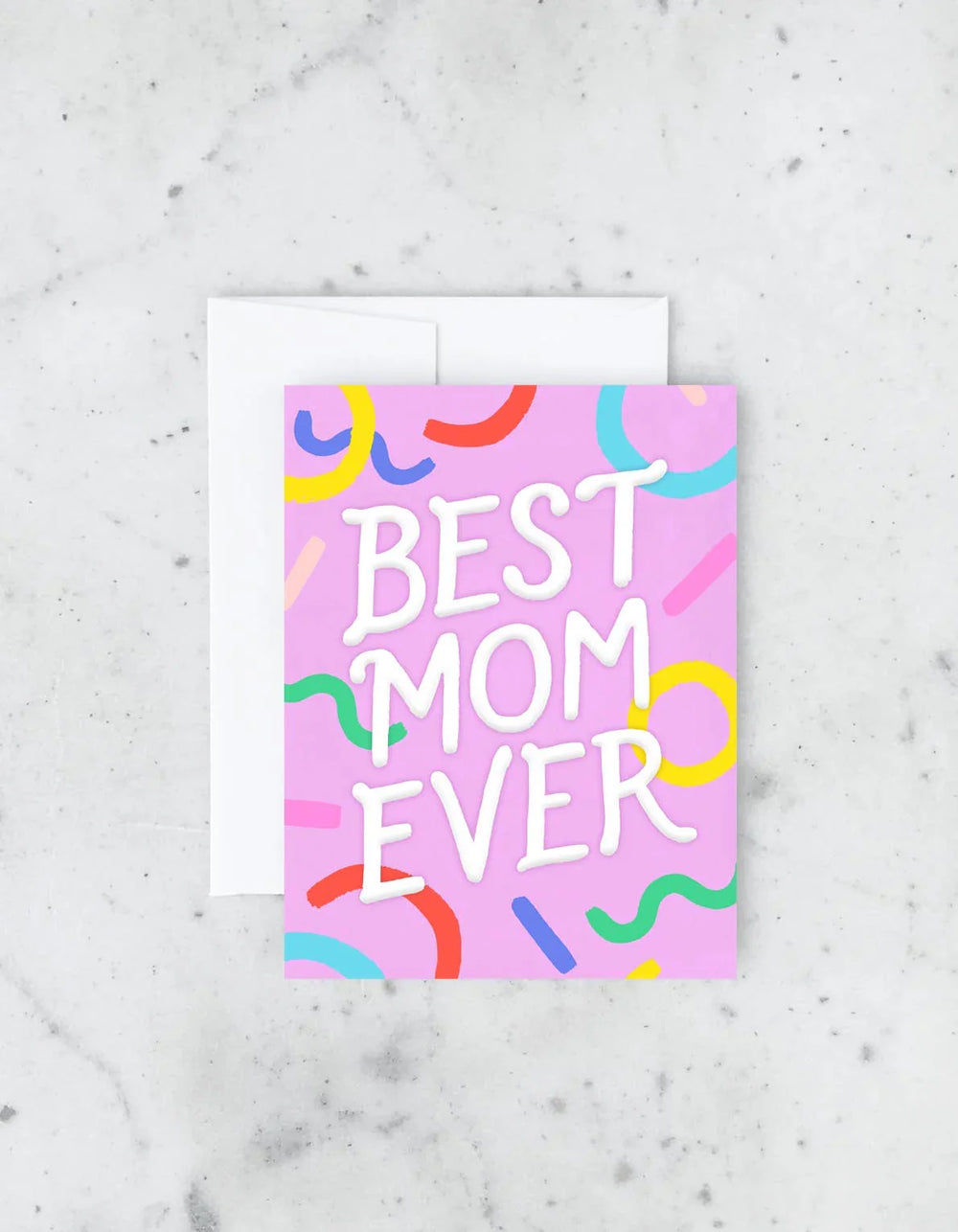 Greeting card with 'Best Mom Ever' text on a pink background with colorful shapes, on a marble surface.