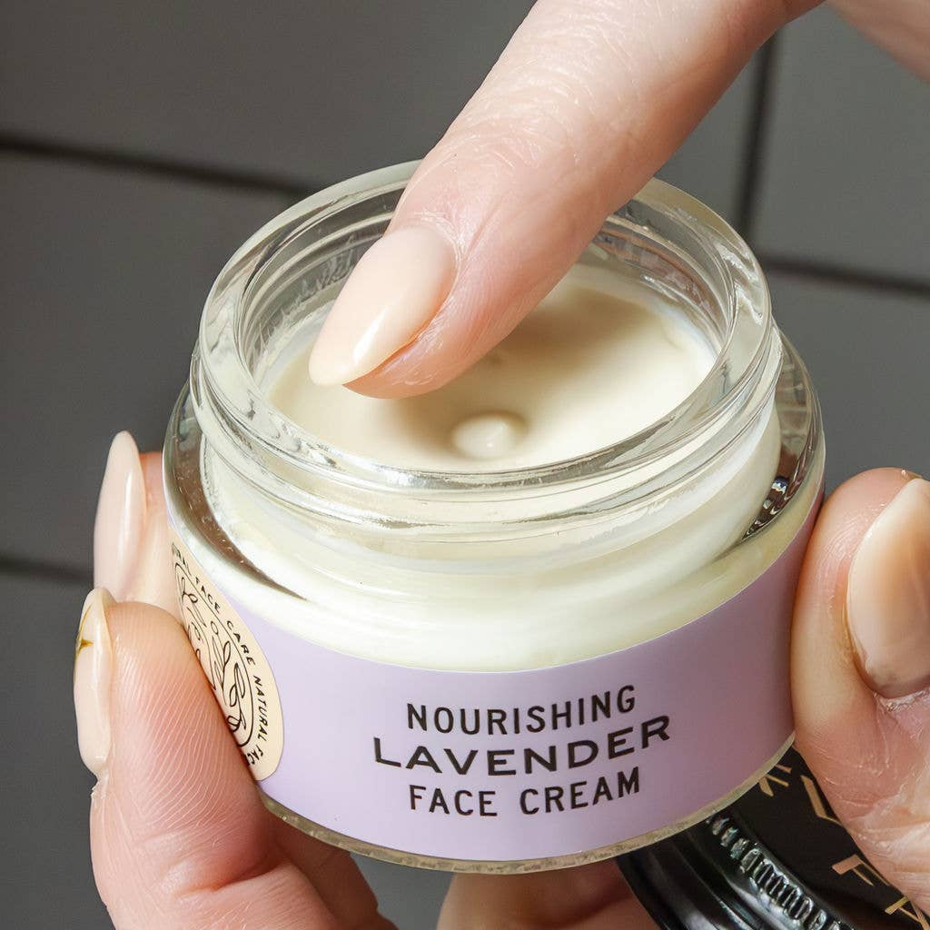 Hand holding a jar of nourishing lavender face cream with a visible brand name.