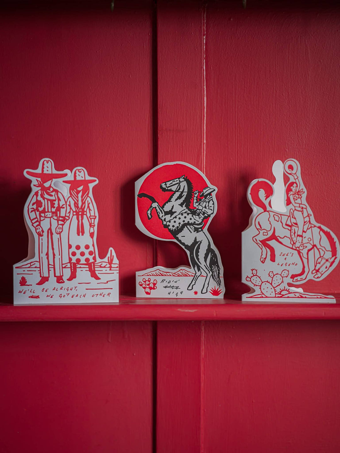 Decorative cutouts of a cowboy, horse, and other figures on a red background