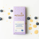 Moonstruck dark chocolate blueberry passion fruit bar packaging on a white background with blueberries and gold drops.