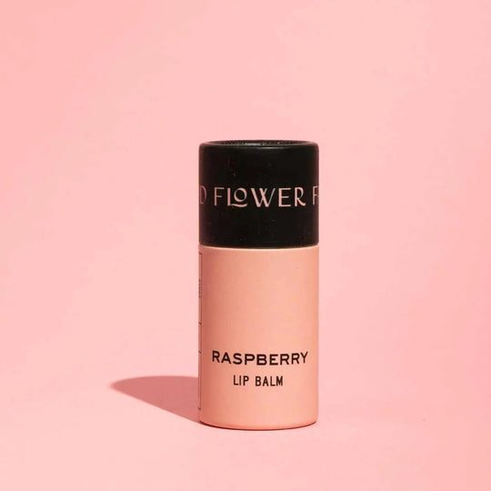 Lip balm with black cap and pink body on a pink background