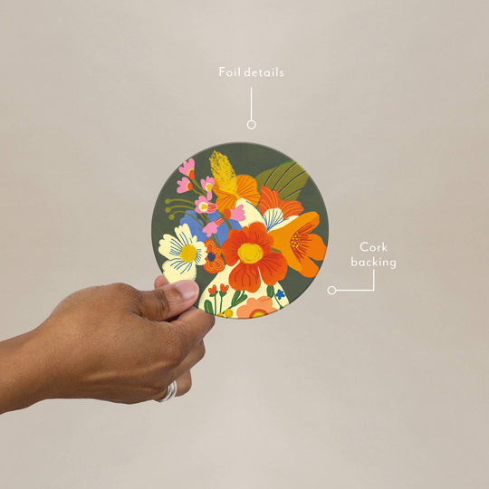 Hand holding a round coaster with floral design, labeled 'Foil details' and 'Cork backing'.